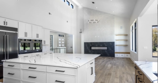 open-concept-kitchen-living-space-remodel-large-island Open-concept kitchen conversion connecting kitchen and living space with large island, white cabinetry, and modern fireplace in adjoining room.