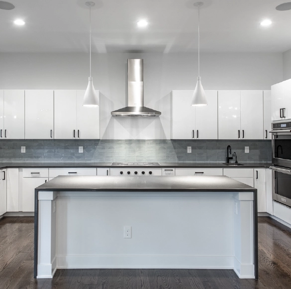 contemporary-white-kitchen-with-large-island Contemporary kitchen featuring white cabinetry, oversized island, stainless steel range hood, and modern tile backsplash for new home and remodeling inspiration.