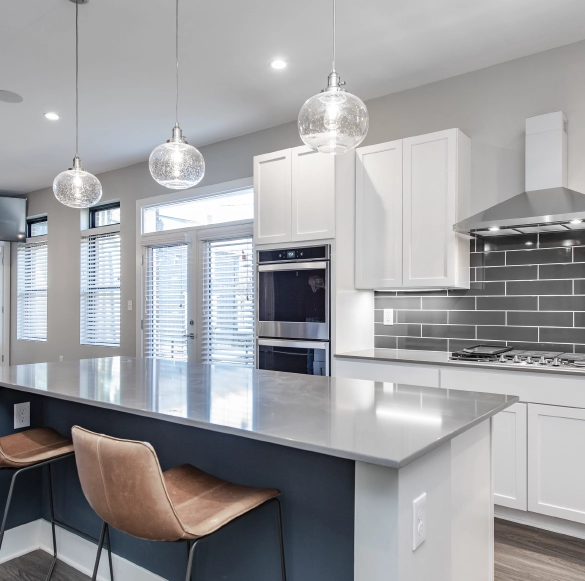 modern-white-kitchen-remodel-design-inspiration Bright modern kitchen featuring white shaker cabinets, gray tile backsplash, quartz countertops, and pendant lighting for luxury home remodeling inspiration.
